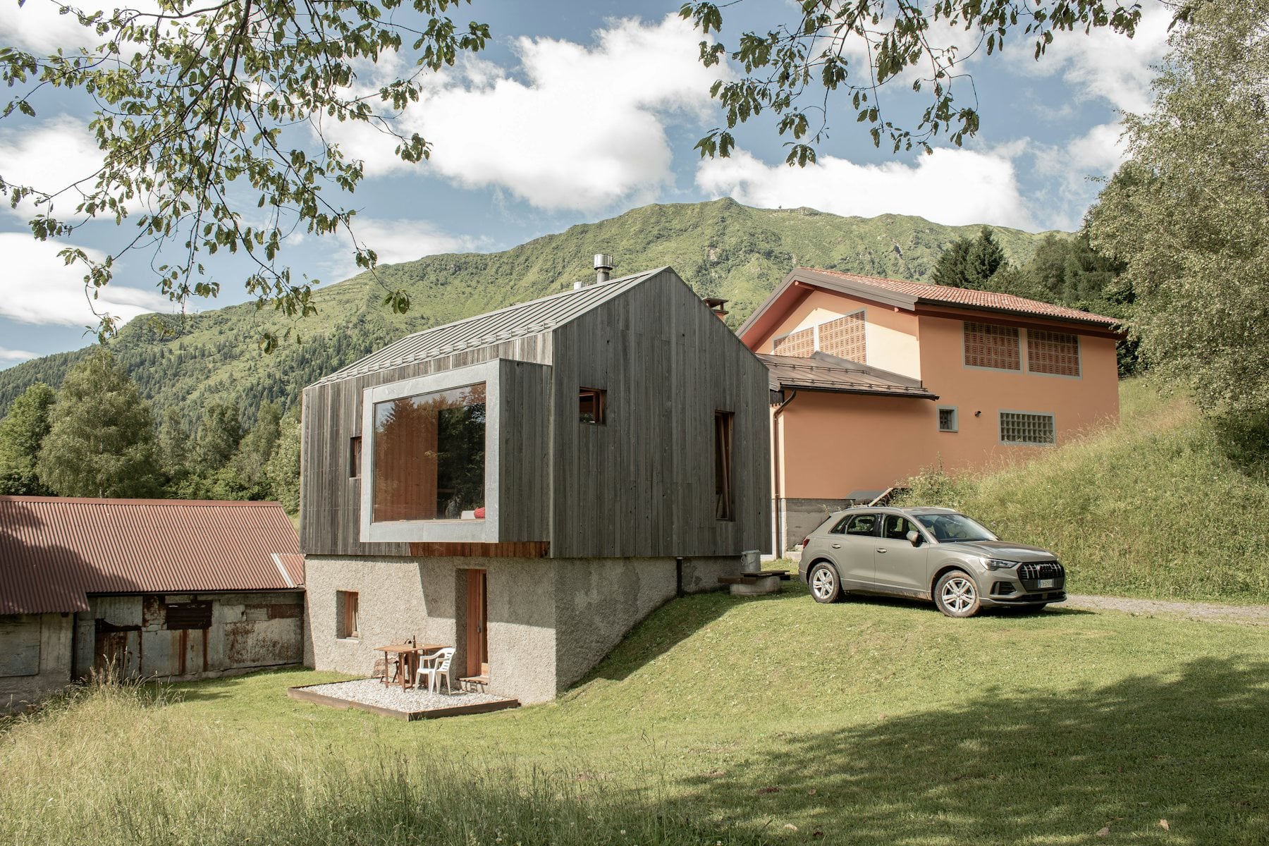 Modernes Holzhaus mit großem Fenster und Wagen davor